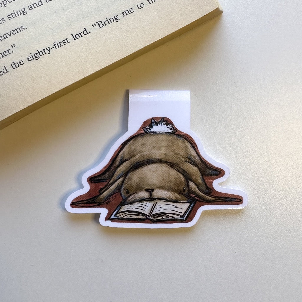 magnetic bookmark of a brown bunny laying flat on it's belly with it's face in  a book. 