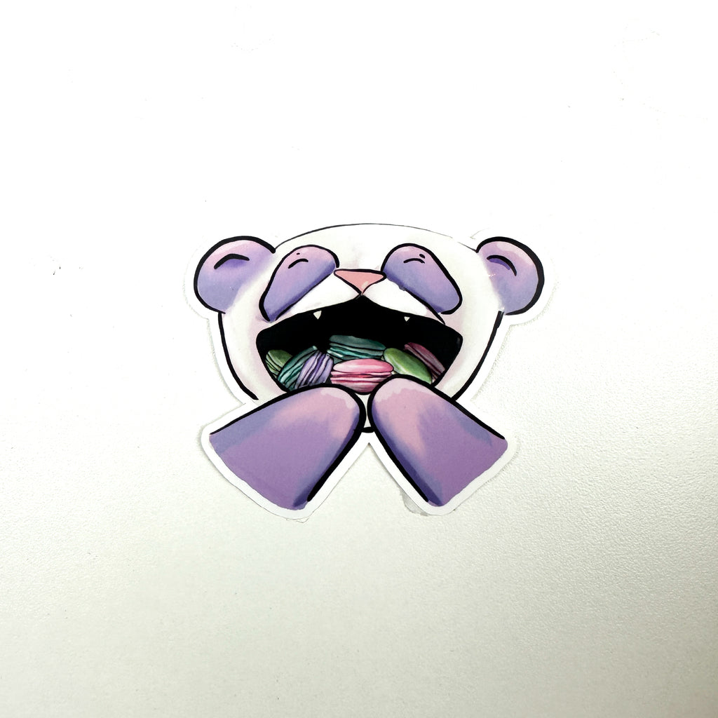 illustrated panda with purple instead of black fur.. The panda's mouth is open and full of pink, green, purple, and teal macarons