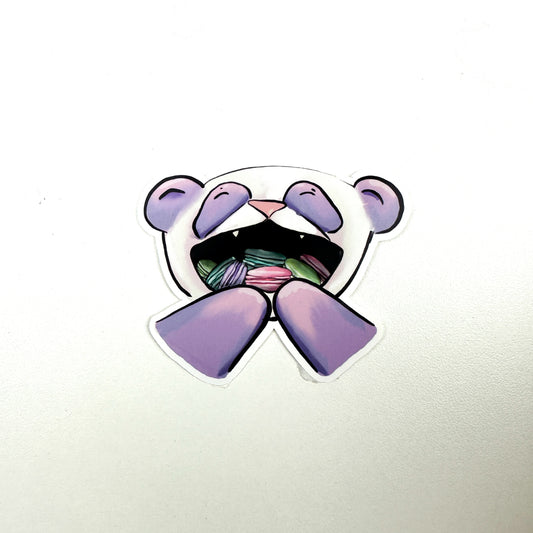 illustrated panda with purple instead of black fur.. The panda's mouth is open and full of pink, green, purple, and teal macarons