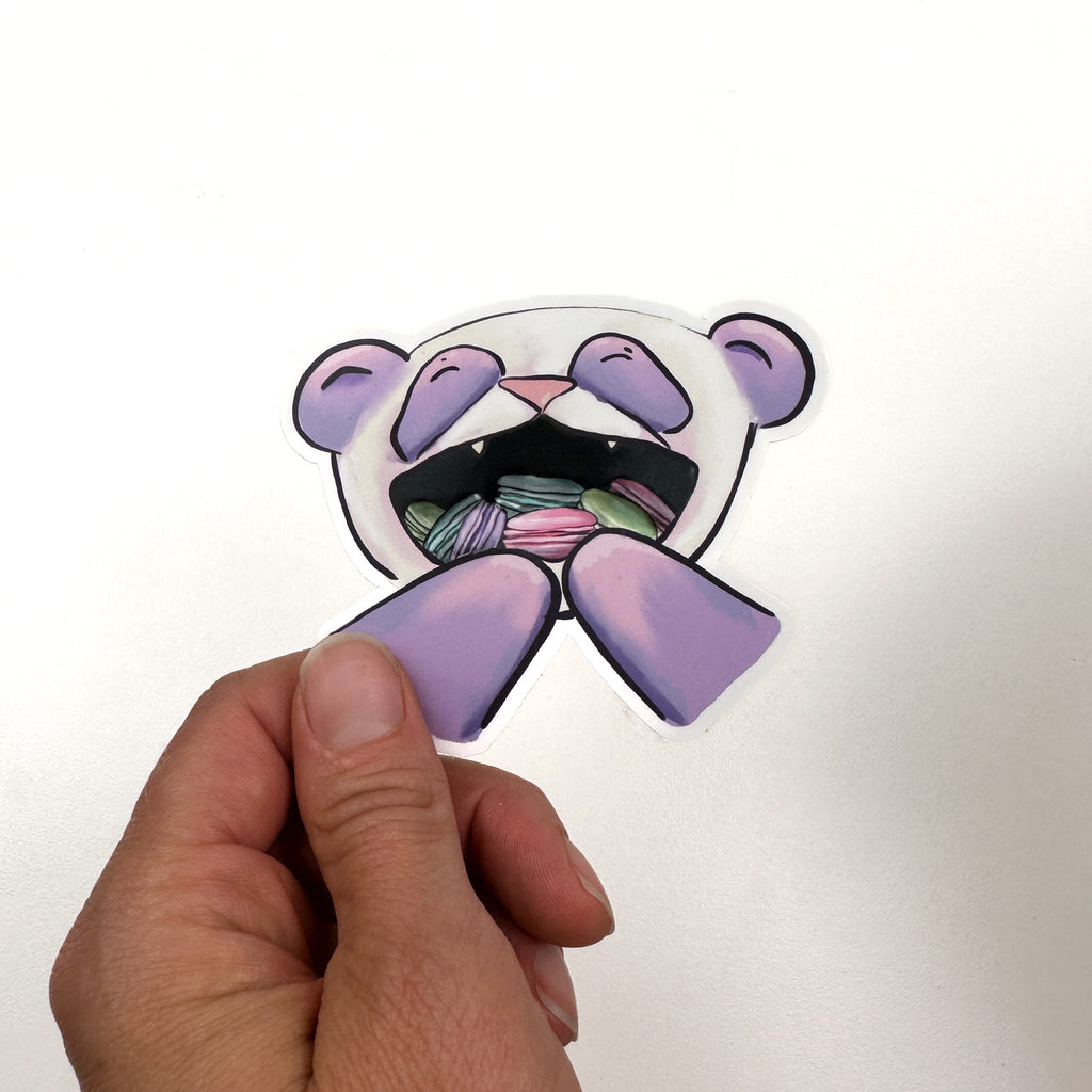 illustrated panda with purple instead of black fur.. The panda's mouth is open and full of pink, green, purple, and teal macarons