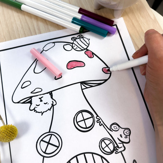 A partially colored coloring page of a tall mushroom with 3 windows on the stem and a round door to enter this cute house. There is a bumble bee above it and a purrfle (character of AEA) hanging from it. Filbert the tree frog is also peaking around the side.