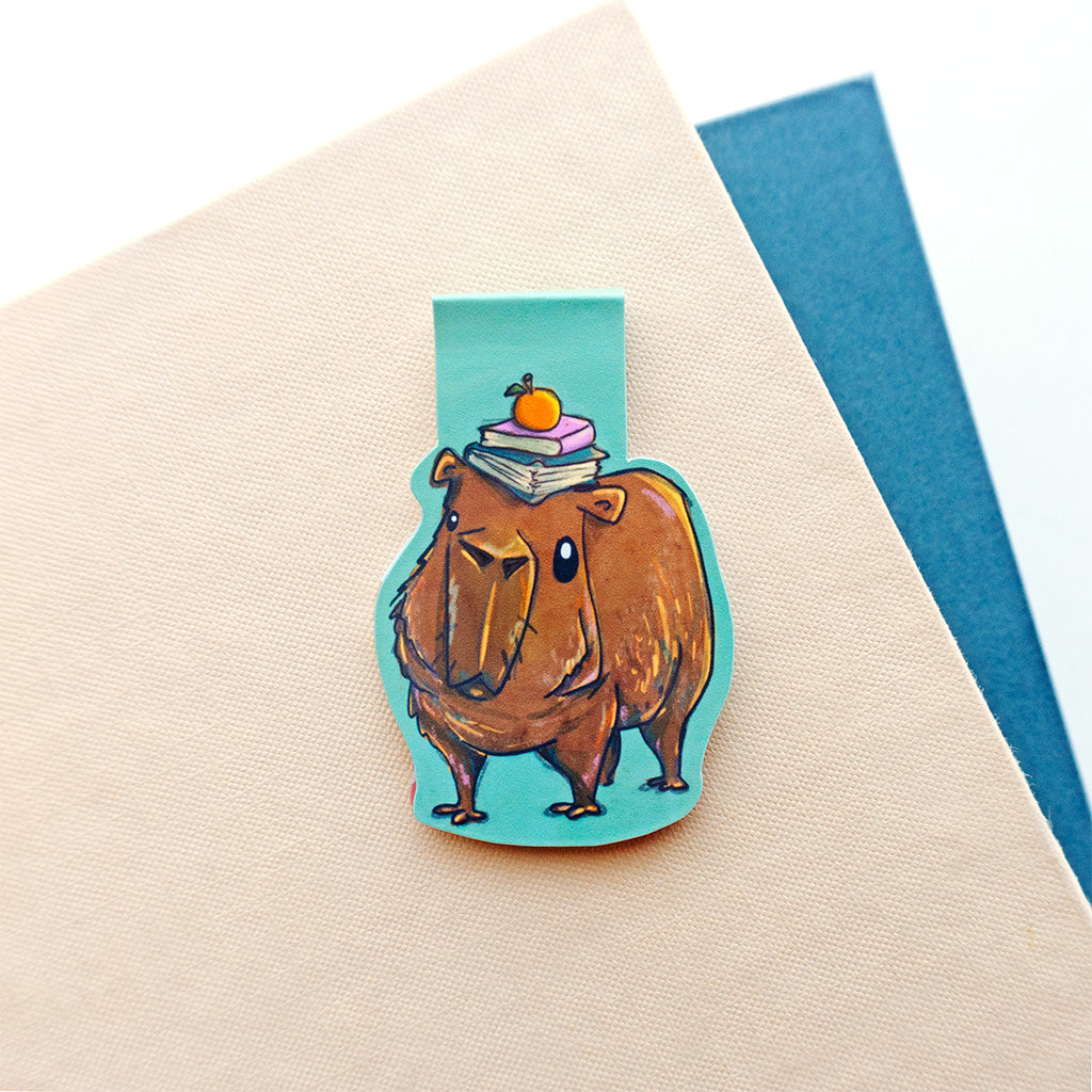 capybara with stack of books on head with teal background bookmark
