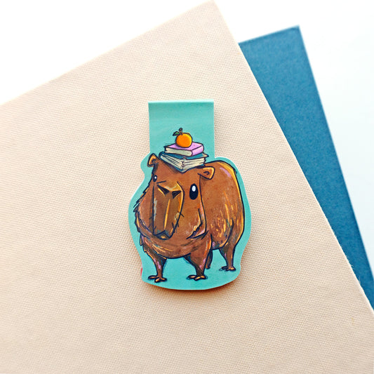 capybara with stack of books on head with teal background bookmark
