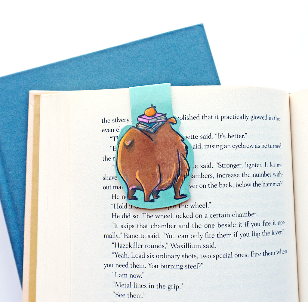 back of capybara bookmark showing its big booty and tail with the stack of books on it's head