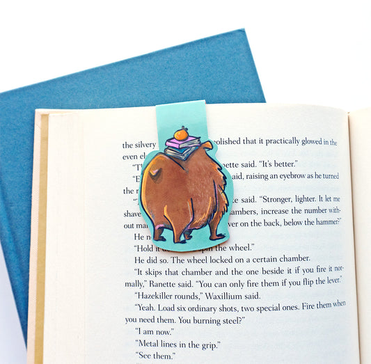 back of capybara bookmark showing its big booty and tail with the stack of books on it's head