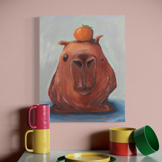 Painting of a capybara's head with an orange on its head, displayed on a wall above colorful mugs and a plate.