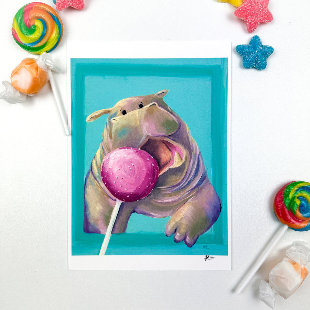 fine art print of cute kawaii style hippo busting out of a border and open mouth going after a pink cake pop. This photo is stylized with candy around. 