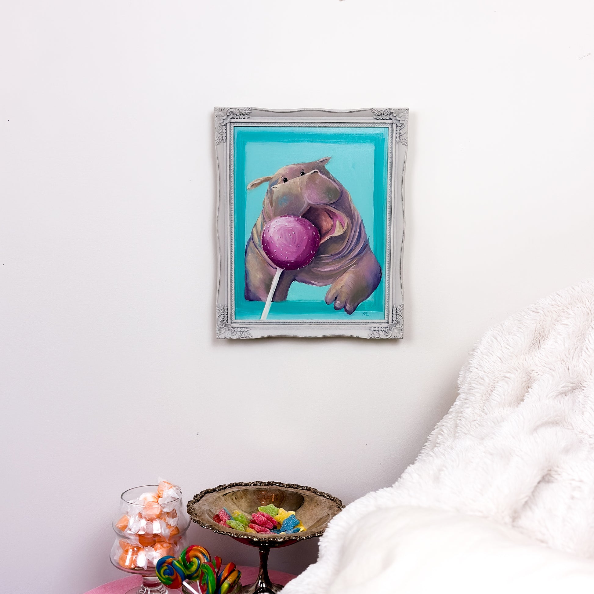 framed oil painting of a cute illustrative and kawaii style hippo that is opening it's mouth, trying to get to a pink cake pop that is in the foreground..