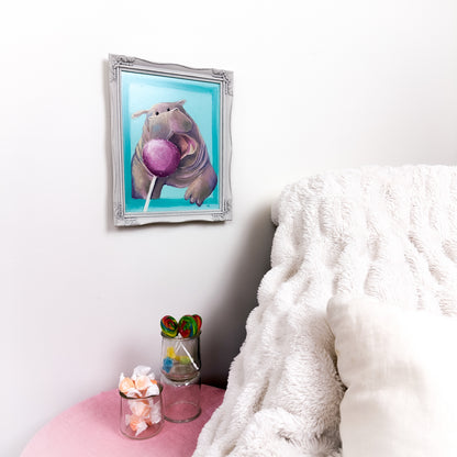 framed oil painting of a cute illustrative and kawaii style hippo that is opening it's mouth, trying to get to a pink cake pop that is in the foreground..