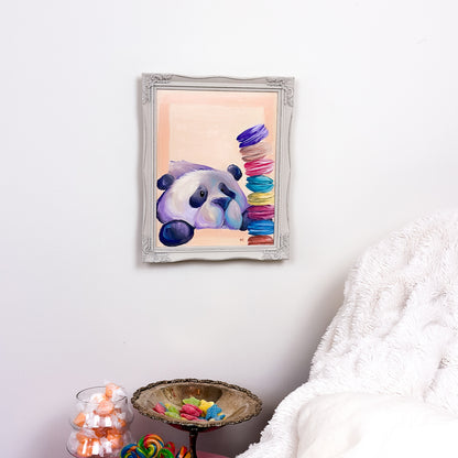 framed painting with a peach colored background of a cute kawaii/illustrative style panda, staring at a stack of colorful macarons. 