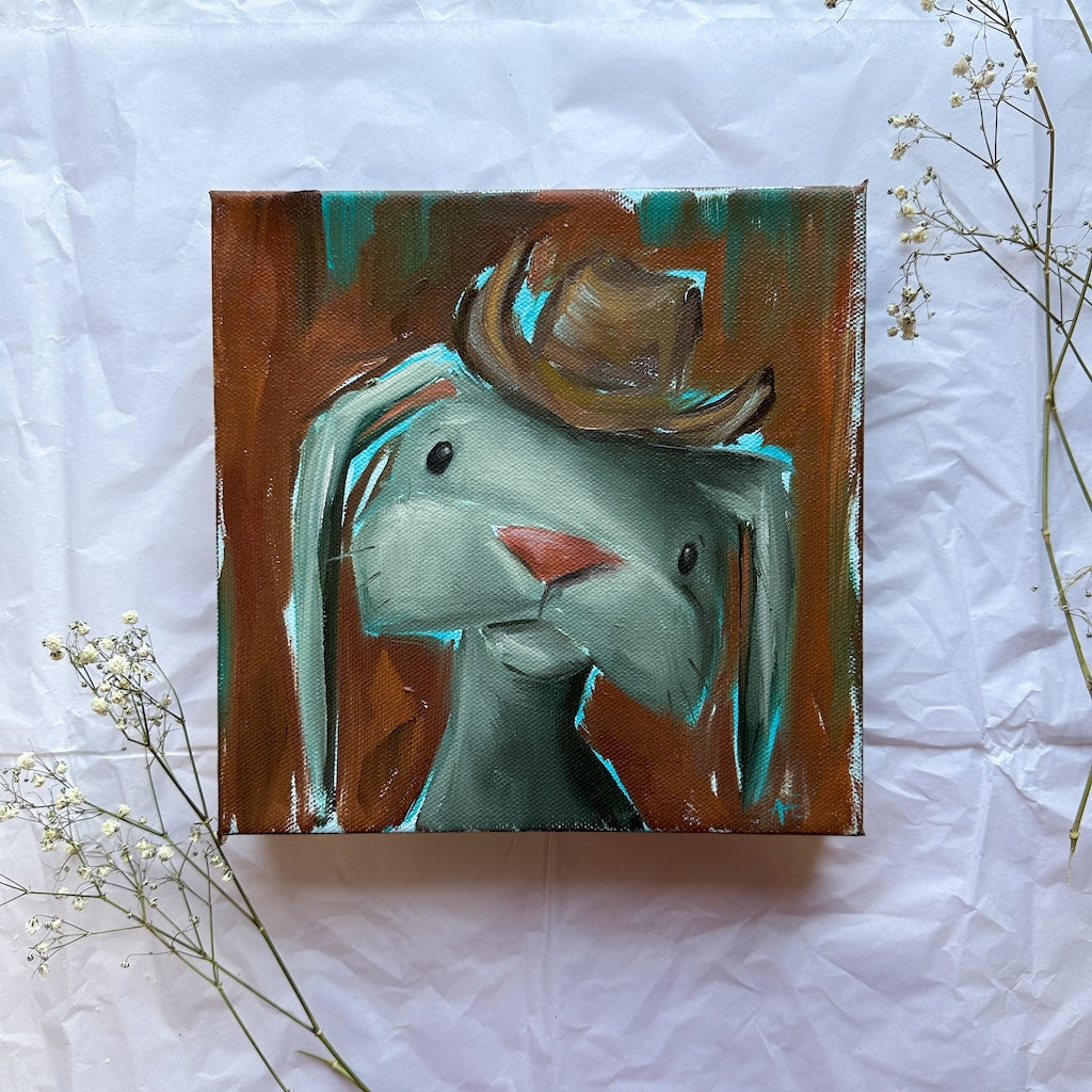 Oil painting of a  bunny wearing a cowboy hat with a rust orange and brown background and turquoise highlights. 