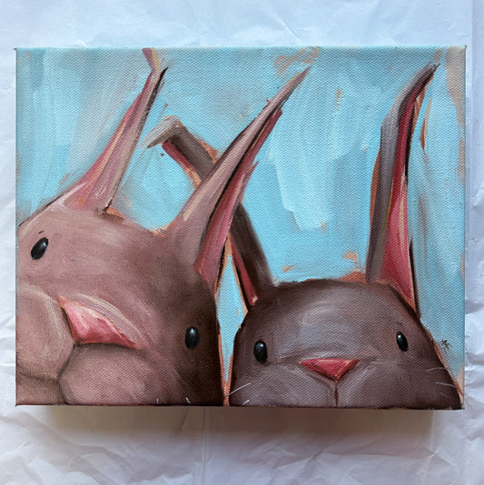 Oil painting with two bunnies peeking their heads up out of the bottom of the canvas. Both bunnies are brown in color and the backround is light blue with some tan accents. 