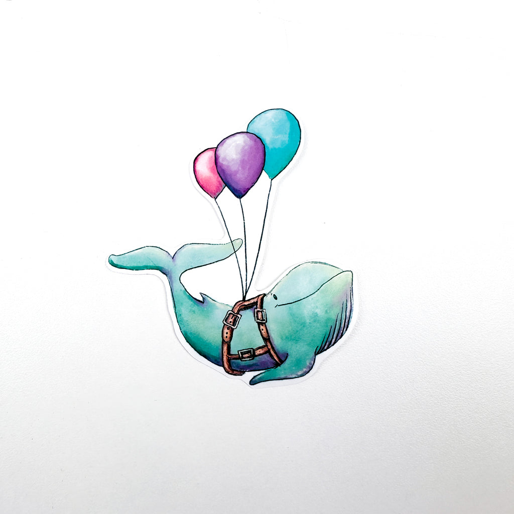 An illustrated sticker of a blue whale with a smile and wearing a harness carried by 3 balloons, pink, purple and blue