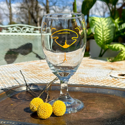 iced tea glass with yellow outline of a bear face on the front. The glass is empty. 