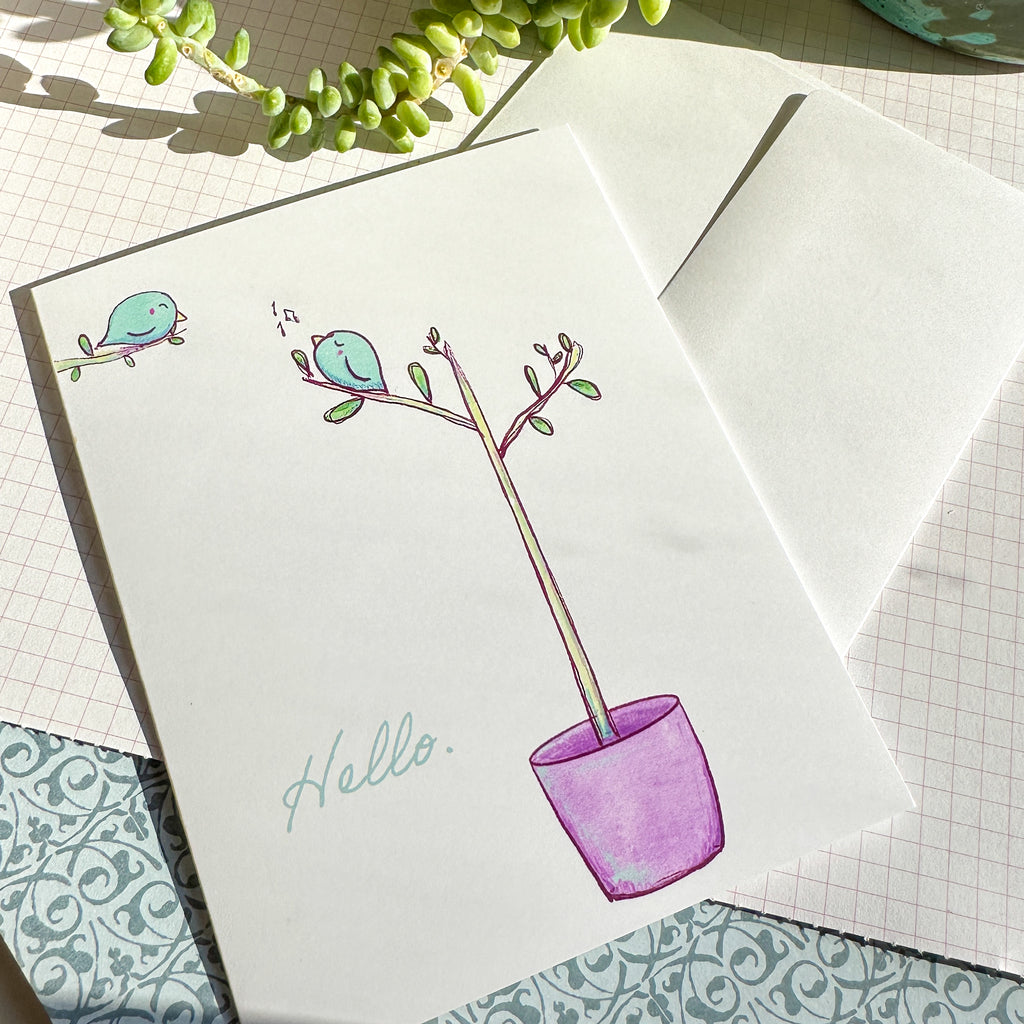 Greeting card in an illustrative style of a blue bird in the upper left corner on a branch and another bird on a potted sapling with music notes near it.  The word HELLO. is written in the bottom left in a script font and light blue. The greeting card is pictured  next  to the included white envelope.